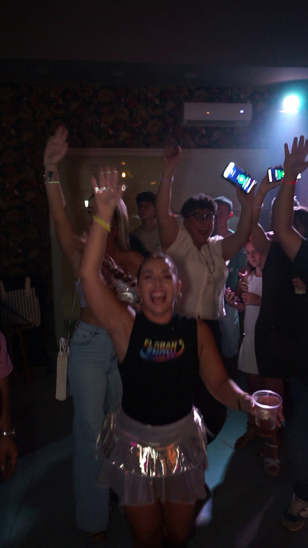 Una animadora y los asistentes celebran con las manos y los móviles en alto